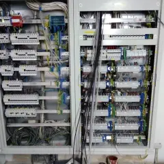 Otwarta skrzynka elektryczna z licznymi przewodami i bezpiecznikami.