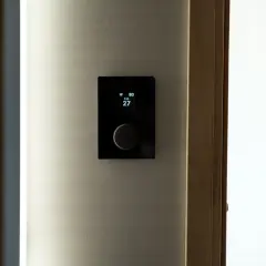 Nowoczesny panel sterowania ogrzewaniem elektrycznym pokazuje 27 stopni.