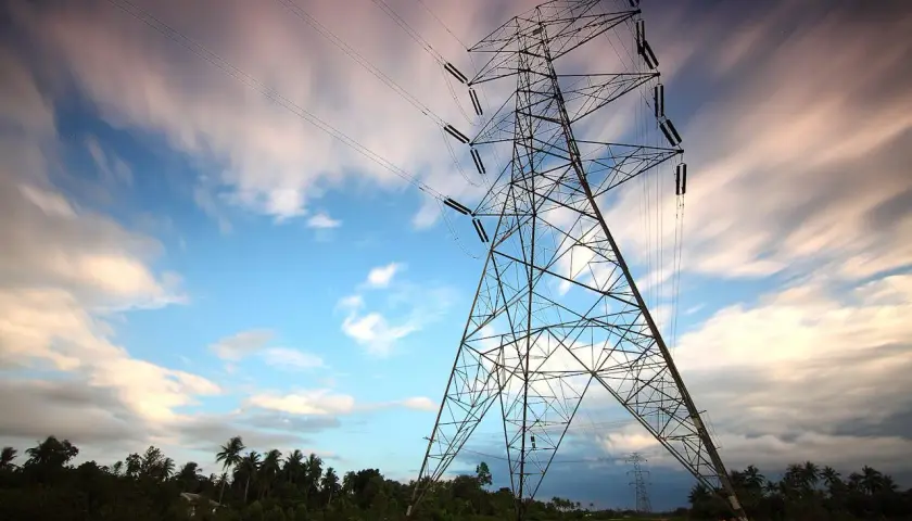Wieża energetyczna na tle nieba z chmurami, jakby w ruchu. Taryfa g13 zapewnia energię.
