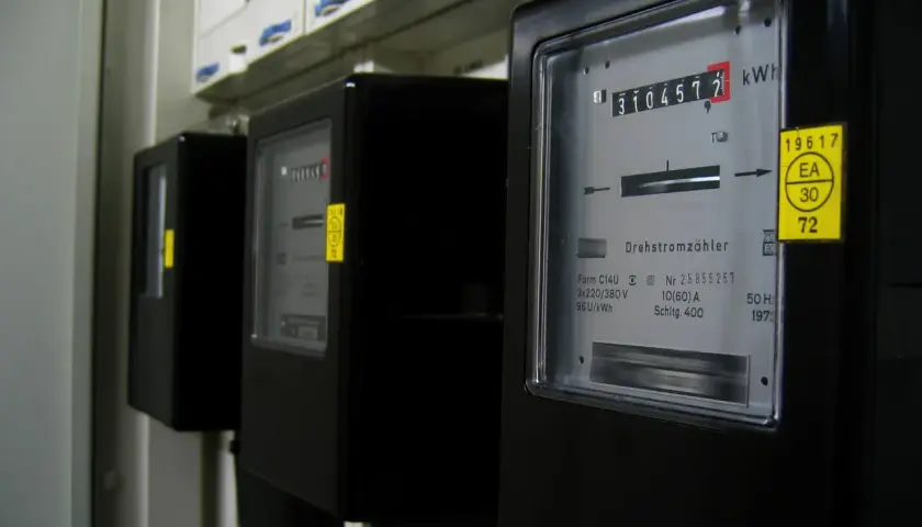 Trzy liczniki energii elektrycznej, każdy z wyświetlaczem pokazującym zużycie w kWh. Jeden z liczników pokazuje 310457.7 kWh.