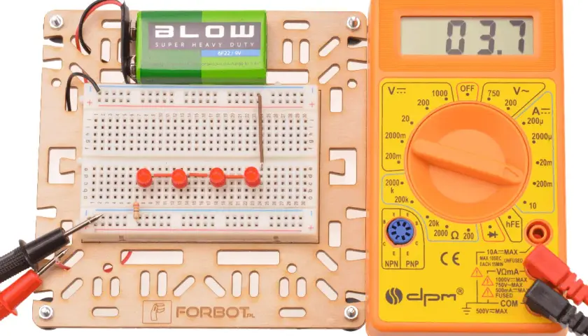 Zestaw do eksperymentów z elektroniką: płytka stykowa, bateria 9V, multimetr i rezystor.