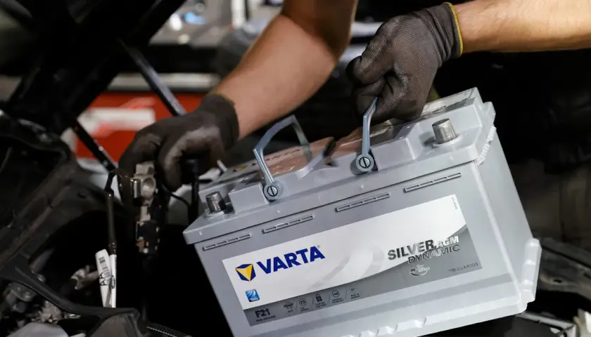 Mechanik w rękawiczkach wymienia akumulator Varta Silver AGM Dynamic, dbając o jego żywotność.